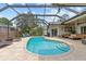 A kidney shaped pool sits in the center of a screened in outdoor living area at 1077 Captains Way, Tarpon Springs, FL 34689
