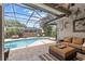 Screened-in outdoor pool area with a view of outdoor seating and lush landscaping at 1077 Captains Way, Tarpon Springs, FL 34689