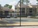 View of a community tennis court, fenced for security, with apartments and parked cars in the background at 13289 Arbor Pointe Cir # 201, Tampa, FL 33617
