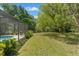 Spacious backyard featuring a screened-in pool area and lush greenery for outdoor enjoyment at 1379 Matthew Ave, Spring Hill, FL 34609