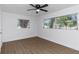 Bright bedroom features wood-look flooring, ceiling fan, and natural light from updated windows at 1432 S Keene Rd, Clearwater, FL 33756