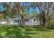 Side view of a charming single-story home with mature trees shading the lawn at 1432 S Keene Rd, Clearwater, FL 33756