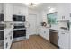 Bright white kitchen with stainless steel appliances, quartz countertops, and a window over the sink at 1432 S Keene Rd, Clearwater, FL 33756