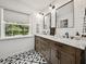 Bathroom with dual sinks, granite countertop, stylish tile floor, subway tile backsplash, and window view at 17515 Drake Ct, Lutz, FL 33559