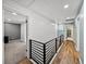 Second story hallway with white shiplap accent wall, modern railing, hardwood flooring, and bedroom access at 17515 Drake Ct, Lutz, FL 33559