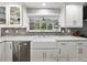 Bright kitchen featuring white cabinets, stainless steel appliances, gray backsplash, and a farm sink at 17515 Drake Ct, Lutz, FL 33559