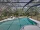Backyard view of a screened pool and patio with hot tub surrounded by lush greenery at 17515 Drake Ct, Lutz, FL 33559
