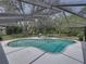 Backyard view of a screened pool and patio with hot tub surrounded by lush greenery at 17515 Drake Ct, Lutz, FL 33559