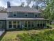 Back exterior of home featuring large windows with natural landscaping and a screened pool area at 17515 Drake Ct, Lutz, FL 33559