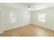 Bright bedroom featuring wood floors, ceiling fan, neutral walls, and natural light from two windows at 2505 Buckhorn Run Dr, Valrico, FL 33596