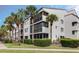 Condo building featuring a clean white facade, screened balconies, and lush tropical landscaping at 2593 Countryside Blvd # 7204, Clearwater, FL 33761