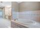 Elegant bathtub with tile surround, next to vanity with dual sinks, and a door leading to another room at 2704 Chambray Ln, Tampa, FL 33611