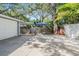 Detached garage and concrete driveway in backyard surrounded by mature trees and shrubbery at 2704 Chambray Ln, Tampa, FL 33611