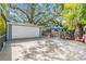 Detached garage and concrete driveway in backyard surrounded by mature trees and shrubbery at 2704 Chambray Ln, Tampa, FL 33611