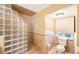 Bathroom features a glass block shower wall and neutral tiling and toilet near window at 2718 W Leila Ave, Tampa, FL 33611