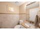 Well-lit half bathroom with a granite countertop, tile walls, and a decorative mirror at 2718 W Leila Ave, Tampa, FL 33611