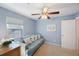 Inviting bedroom with a blue sofa, wood dresser, and plenty of natural light from a window at 2718 W Leila Ave, Tampa, FL 33611