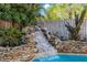 Backyard pool featuring a custom rock waterfall feature and lush landscaping at 2718 W Leila Ave, Tampa, FL 33611