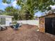 Backyard view with chairs around fire pit, fenced perimeter and stone building at 2720 Wiltshire Ave, Palm Harbor, FL 34685
