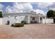 Charming single-story home with a large brick driveway, manicured landscaping, and quaint front porch seating at 2805 W Patterson St, Tampa, FL 33614
