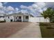 Charming single-story home with a large brick driveway, manicured landscaping, and quaint front porch seating at 2805 W Patterson St, Tampa, FL 33614