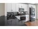 Bright kitchen featuring white cabinets, black countertops, stainless steel appliances, and a stylish backsplash at 302 Summer Sails Dr, Valrico, FL 33594