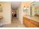 Long bathroom hallway with double mirrors over the vanity, carpet, and an open bedroom view at 30526 Annadale Dr, Wesley Chapel, FL 33545