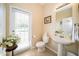 Bathroom features a pedestal sink, toilet, framed mirror, tile floor, and a door leading to the outdoors at 30526 Annadale Dr, Wesley Chapel, FL 33545