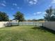 Spacious back yard with lawn, a lake view, and white picket fence for peaceful outdoor living at 32699 Dashel Palm Ln, Wesley Chapel, FL 33543
