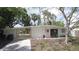 Charming white brick home featuring a pink front door, well-manicured lawn and a carport at 4735 W Wisconsin Ave, Tampa, FL 33616