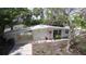 Charming white brick home featuring a pink front door, well-manicured lawn, and a carport at 4735 W Wisconsin Ave, Tampa, FL 33616