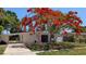 Inviting home with mature tree, featuring a brick facade, a pink door, and a convenient carport at 4735 W Wisconsin Ave, Tampa, FL 33616