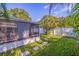 Beautiful backyard featuring a screened lanai, stone paver walkway, lush grass, and palm trees at 6219 57Th N Ave, St Petersburg, FL 33709