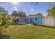 Green backyard featuring a screened lanai, lush lawn, and tropical palm trees at 6219 57Th N Ave, St Petersburg, FL 33709