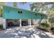 Coastal home with a vibrant turquoise exterior, ground-level garage, and staircase leading to the main entrance at 7417 Seagull Way, Tampa, FL 33635
