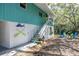 Home featuring a bright turquoise exterior, a ground-level parking, outdoor seating, and a staircase entrance at 7417 Seagull Way, Tampa, FL 33635