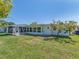 A bright, spacious backyard featuring a white house and a well-maintained lawn under a clear blue sky at 9024 140Th Way, Seminole, FL 33776