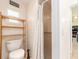 Bright bathroom with a toilet, wooden shelf, shower with curtain, and window allowing natural light to filter in at 9024 140Th Way, Seminole, FL 33776