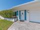 Close up of the home's entrance showcasing the door, blue shutters, and well-maintained landscaping at 9024 140Th Way, Seminole, FL 33776