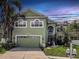 Charming two-story green home featuring lush landscaping and a spacious two-car garage at 11102 Avery Oaks Dr, Tampa, FL 33625