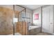 Modern bathroom with a glass enclosed shower, soaking tub, and neutral toned tile at 11720 Navajo Sandstone St, Riverview, FL 33579