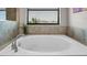 Large soaking tub by a window with view in neutral toned bathroom at 11720 Navajo Sandstone St, Riverview, FL 33579
