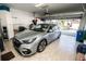 A tidy garage featuring a silver car, white cabinets, an open garage door, and epoxy flooring at 1257 Lyndhurst Greens Dr, Sun City Center, FL 33573
