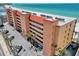 Aerial view of multi-story condominium building on the beach, featuring a red roof and lush landscaping at 13720 Gulf Blvd # 305, Madeira Beach, FL 33708