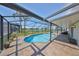 Screened-in pool area with brick patio, clear blue swimming pool, and a serene lake view in the background at 1604 Storington Ave, Brandon, FL 33511