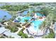 Aerial view of a luxurious community pool, with palm trees and a lake in the background at 215 Oceania Ct, Apollo Beach, FL 33572