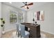 Bright home office with a dark wood desk and two blue chairs, creating an elegant workspace with ample natural light at 215 Oceania Ct, Apollo Beach, FL 33572
