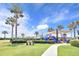 Community playground features modern play equipment, mature palm trees and ample green space at 215 Oceania Ct, Apollo Beach, FL 33572