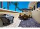 Paver patio with grill and outdoor table and chairs, umbrella, surrounded by yellow walls and palm trees at 2246 Sifield Greens Way # 36, Sun City Center, FL 33573