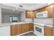 Kitchen with wooden cabinets, white appliances, and view into the living area at 2650 Countryside Blvd # A104, Clearwater, FL 33761